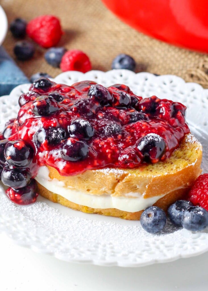 close up photo of french toast on white plate with cheesecake filling and berries