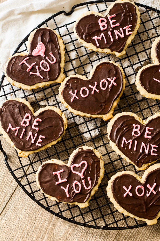 valentines day shortbread heart cookies with chocolate frosting on a cooling rack