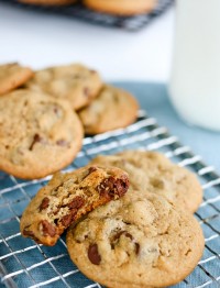 Peanut butter chocolate chip cookies on a cooling rack with a half eaten cookie beside them.