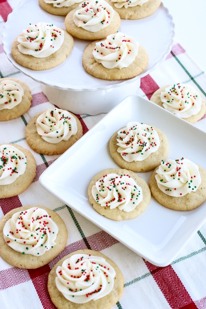 Christmas sugar cookies with white icing and sprinkles on top.