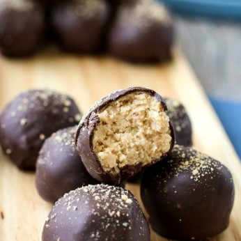 Close up shot of a finished peanut butter balls dipped in chocolate with a bite taken out of it to show delicious inner mixture.
