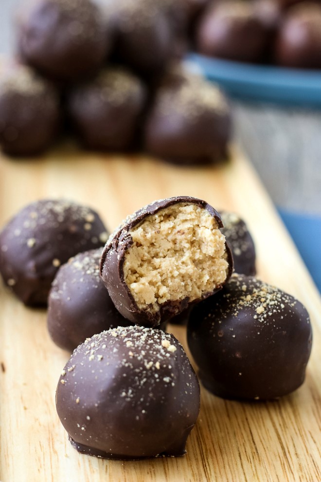 Close up shot of a finished peanut butter balls dipped in chocolate with a bite taken out of it to show delicious inner mixture.