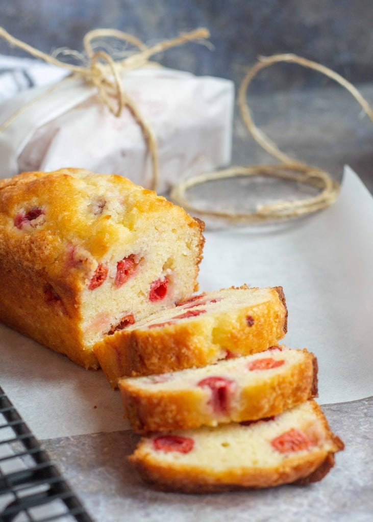 the golden crust of a loaf of cherry almond bread is visible as it has been sliced