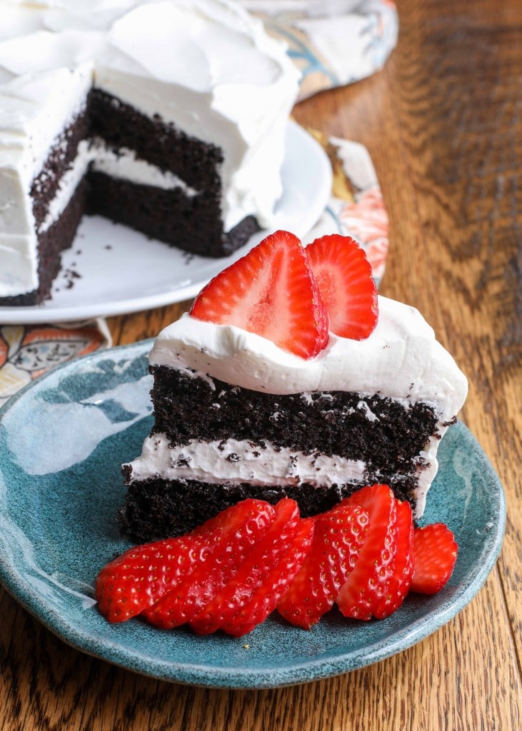 chocolate cake with whipped cream frosting on a blue plate with berries