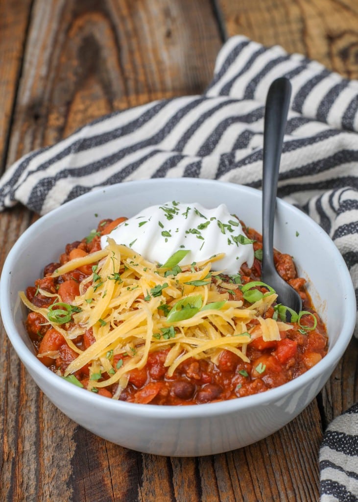 crockpot chili in bowl with spoon and sour cream