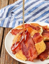 syrup pouring over pancakes with bacon