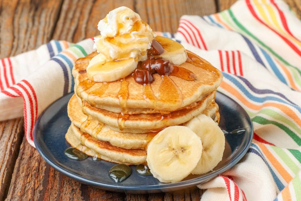 Banana Chocolate Chip Pancakes with sliced bananas, whipped cream, and syrup