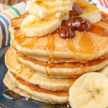 stacked pancakes with chocolate chips, bananas, and syrup