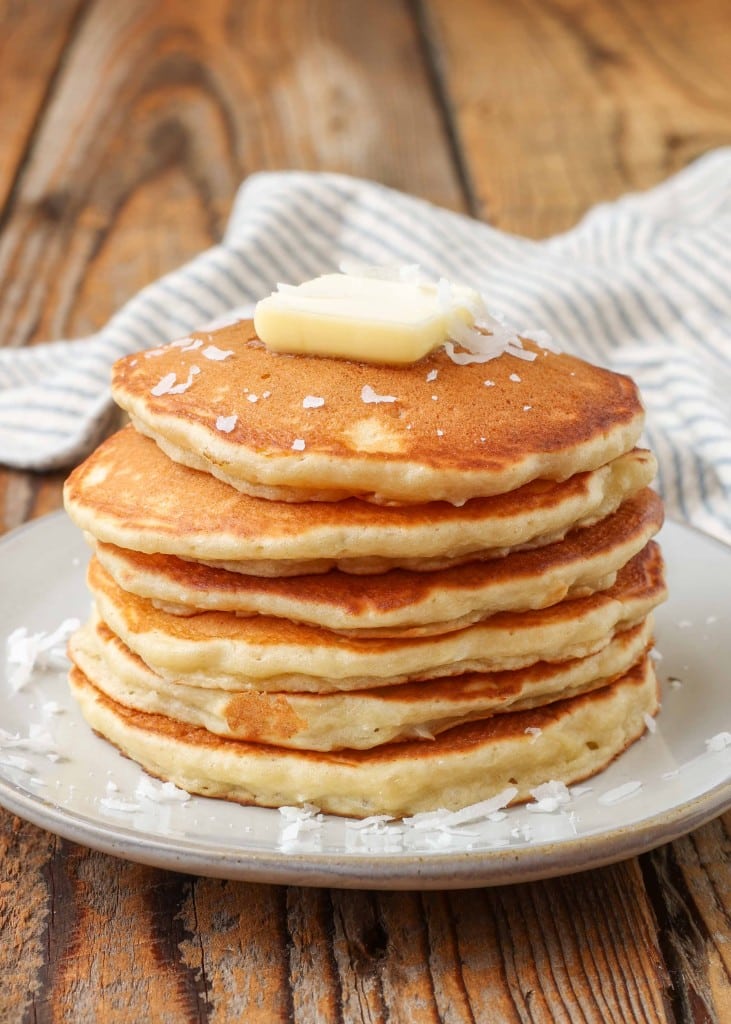 stacked pancakes topped with butter and shredded coconut 