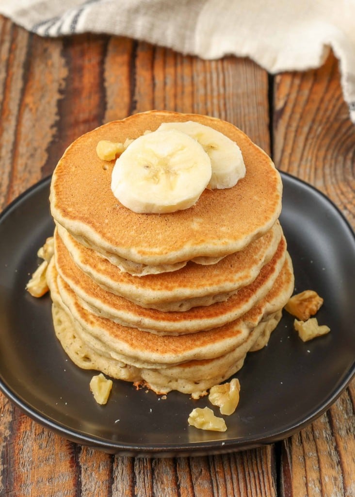 banana pancakes with nuts on small black plate