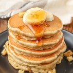 stacked pancakes with bananas on plate with syrup