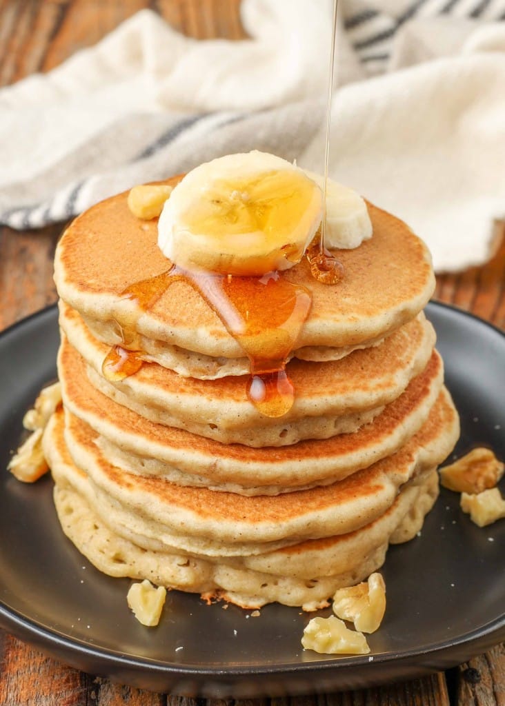 stacked pancakes with bananas on plate with syrup