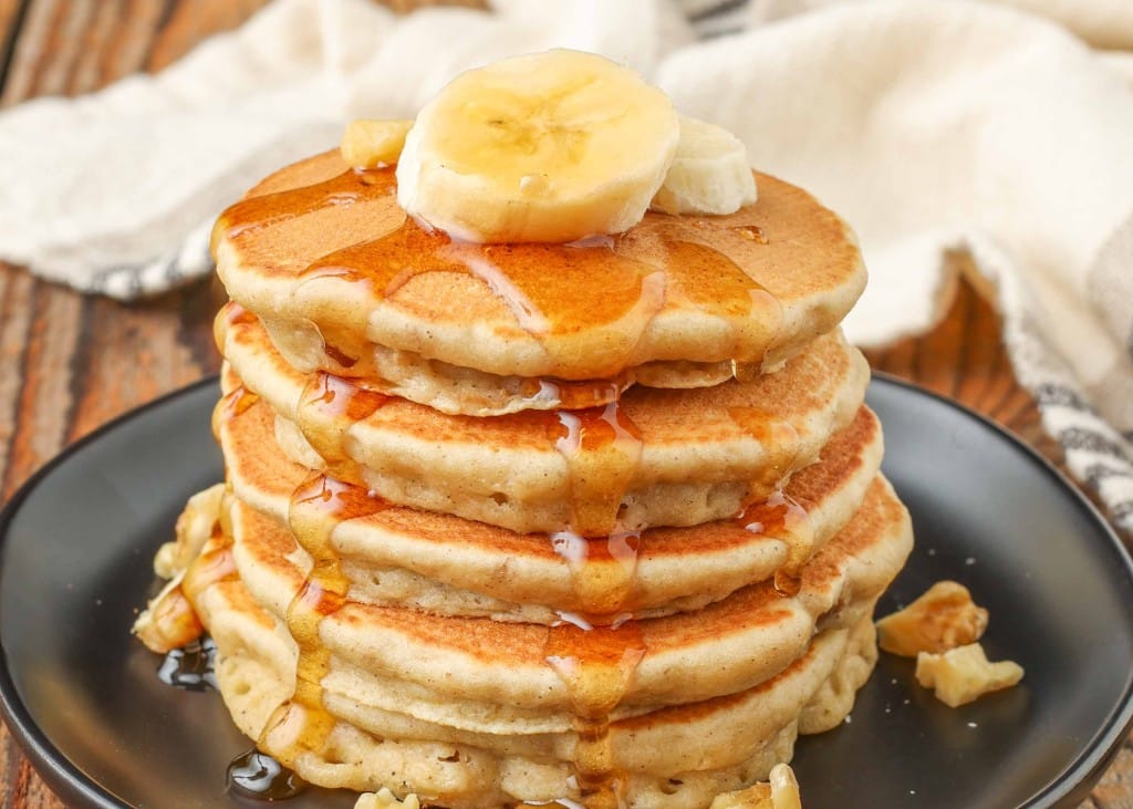 pancakes with bananas, pecans, and syrup on plate