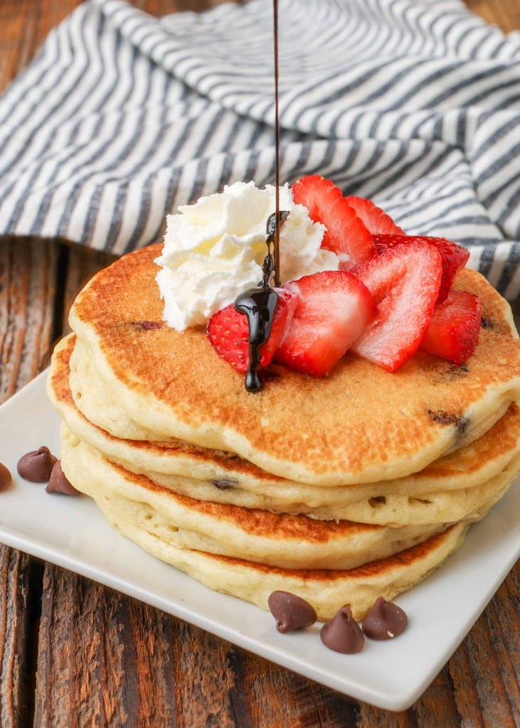 Chocolate Chip Pancakes stacked on square plate with berries and whipped cream