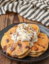 chocolate chip pancakes on plate with whipped cream and syrup