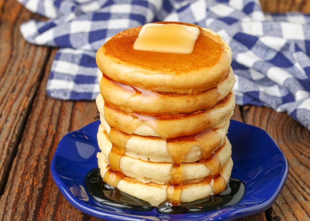 miniature pancakes stacked on tiny blue plate with butter and syrup