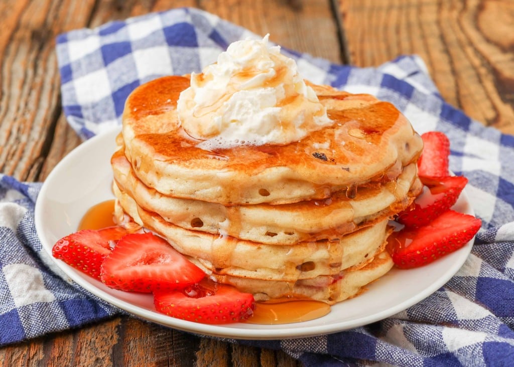 pancakes with strawberries on small plate with whipped cream
