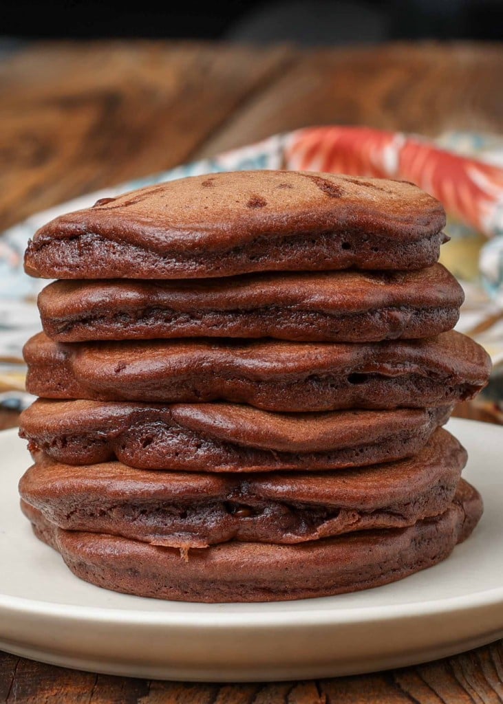 chocolate pancakes stacked on cream colored plate