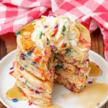 sliced sprinkle pancakes with whipped cream and syrup
