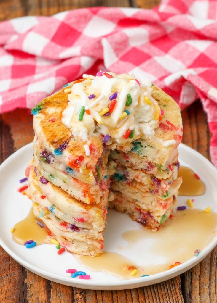 sliced sprinkle pancakes with whipped cream and syrup