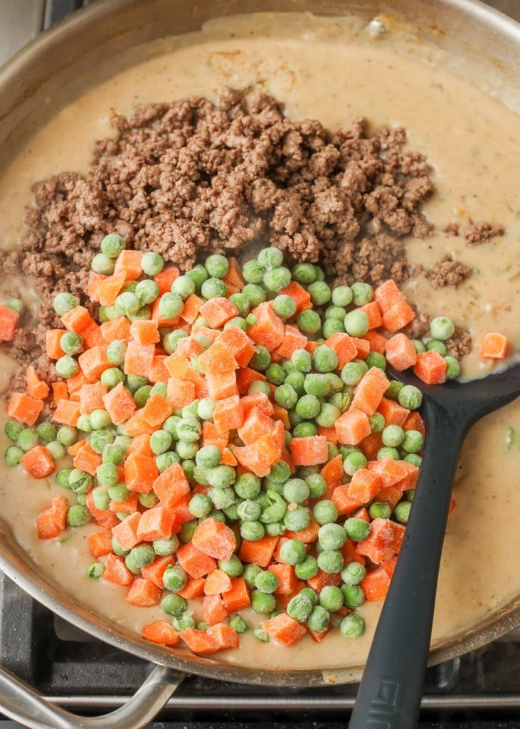 Ground Beef Pot Pie gravy filling with ground beef and peas and carrots on top