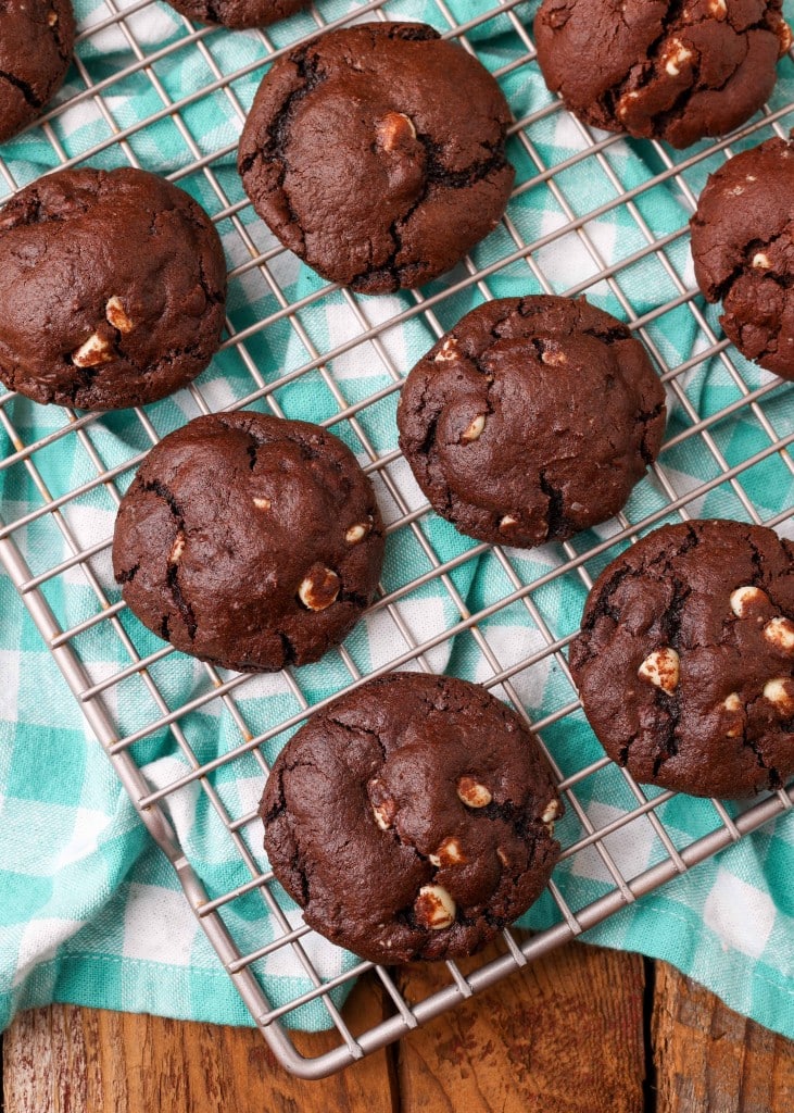 thick and chewy triple chocolate chip cookies rest on a cooling rack over a cyan tea towel