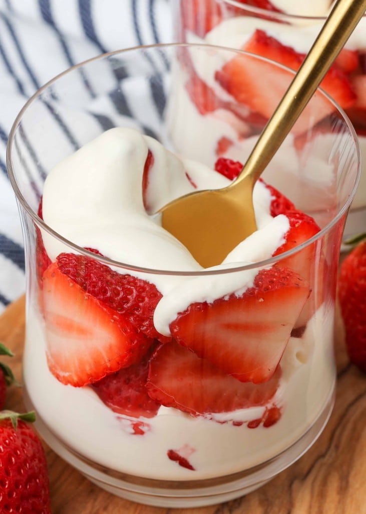 a vertical photo of a ball glass with layers of sweet cream and strawberries visible inside