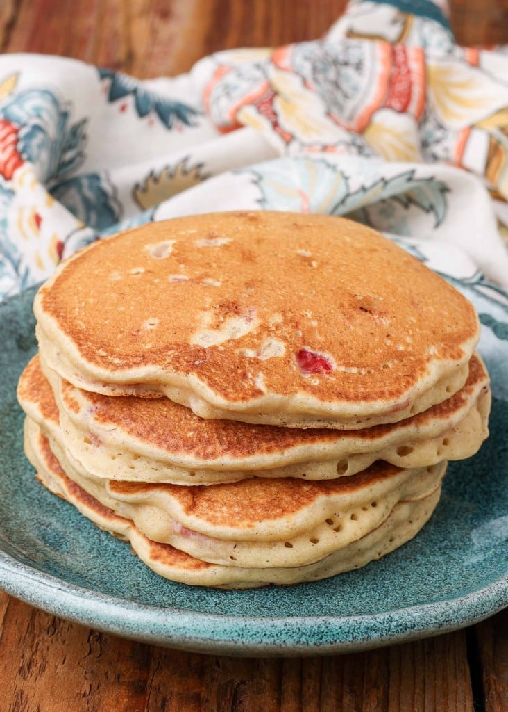pancakes stacked on light blue plate with floral cloth in background