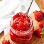 Strawberry Compote in glass jar with spoon and fresh berries