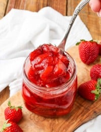 Strawberry Compote in glass jar with spoon and fresh berries