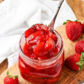 Strawberry Compote in glass jar with spoon and fresh berries