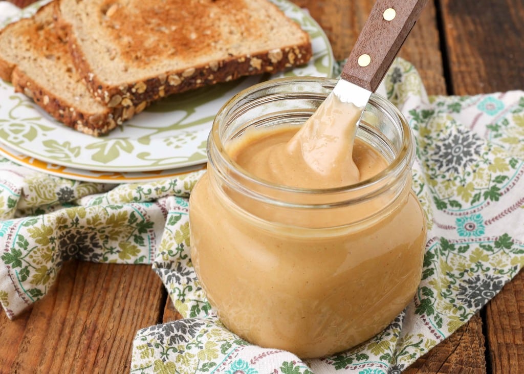Amish style peanut butter in jar with wooden handled knife next to toast