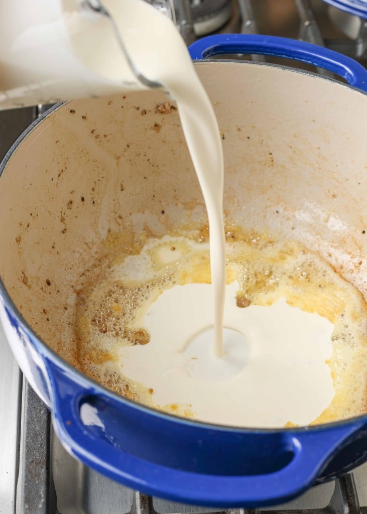 Overhead shot of butter and heavy cream cooking in a blue pot
