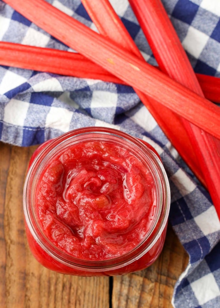 fresh rhubarb sauce in jar with silver spoon next to blue checkered napkin
