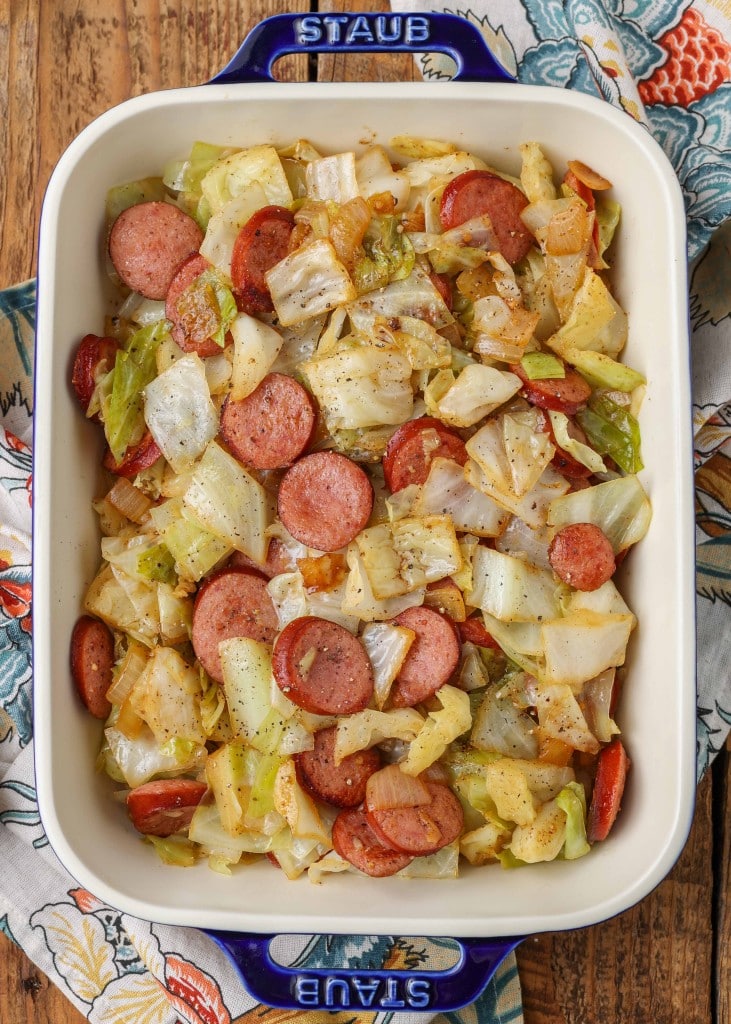 Overhead vertical shot of kielbasa cabbage stir fry, served in a long white rectangular tray