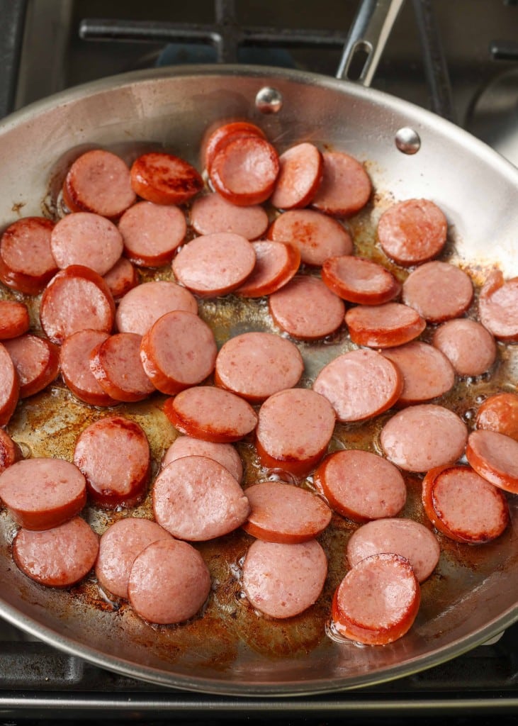 Sizzling kielbasa sausage in a stainless steel skillet