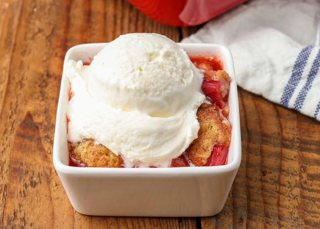 a horizontal shot of the serving of cobbler topped with vanilla ice cream, ready to eat