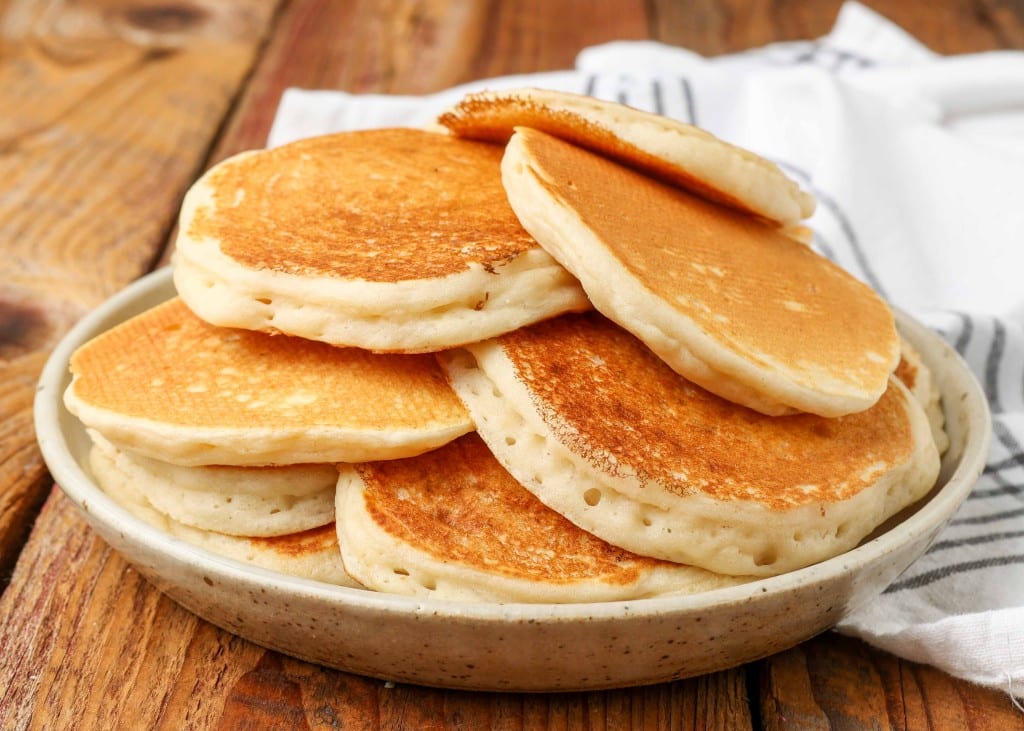 plain pancakes stacked on a pottery plate