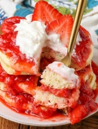 Bite of stacked strawberry pancakes on gold fork