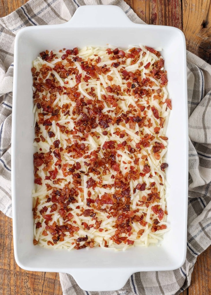 Crumbled bacon has been spread evenly over the top of the shredded cheese.