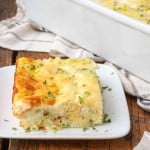 A Horizontal photo of a serving of Amish breakfast casserole on a square white plate over a wooden tabletop.