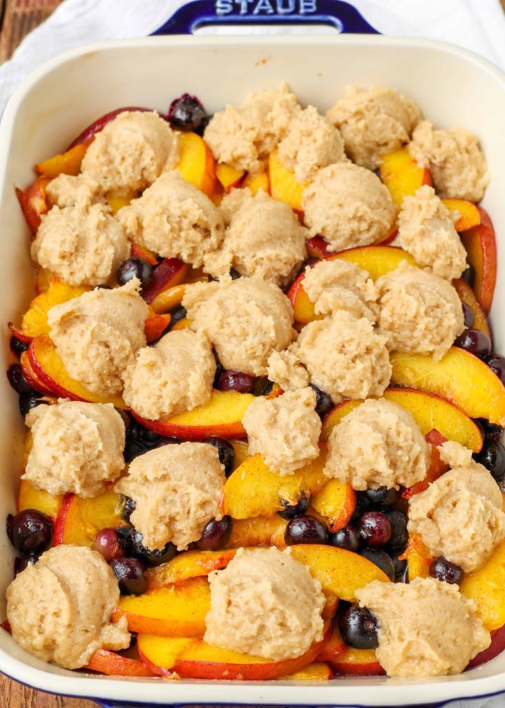 scoops of dough for the cobbler crust have been placed atop the fresh fruit in a white baking dish
