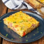 A horizontally aligned photo of a serving of Crescent Roll Breakfast Casserole on a blue plate with a blue and white towel visible in the background.