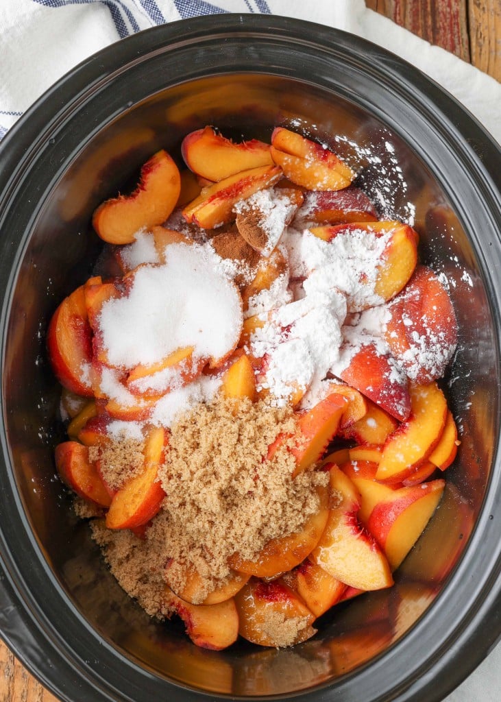 The peaches and spices and sugars have been added to the crock pot and are ready to stir.