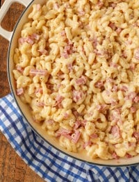 A vertically aligned, top down photo of a white pan full of mac and cheese with tiny chunks of ham in it.
