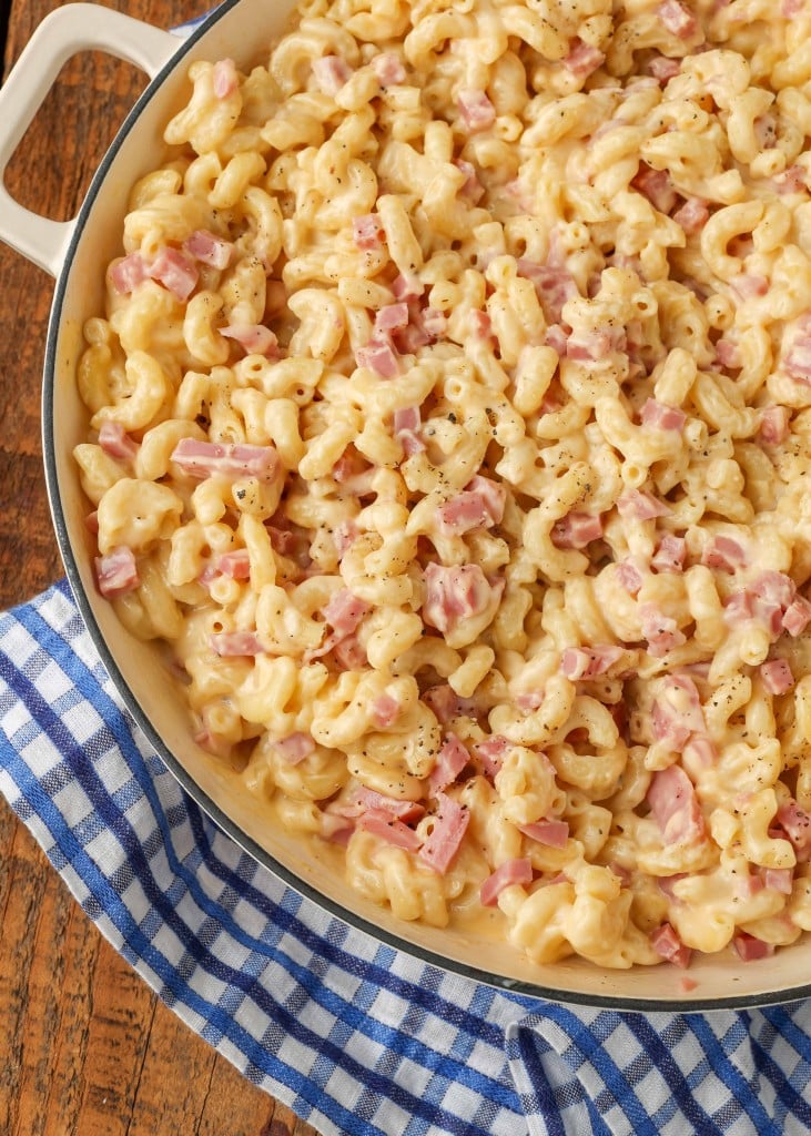 A vertically aligned, top down photo of a white pan full of mac and cheese with tiny chunks of ham in it.