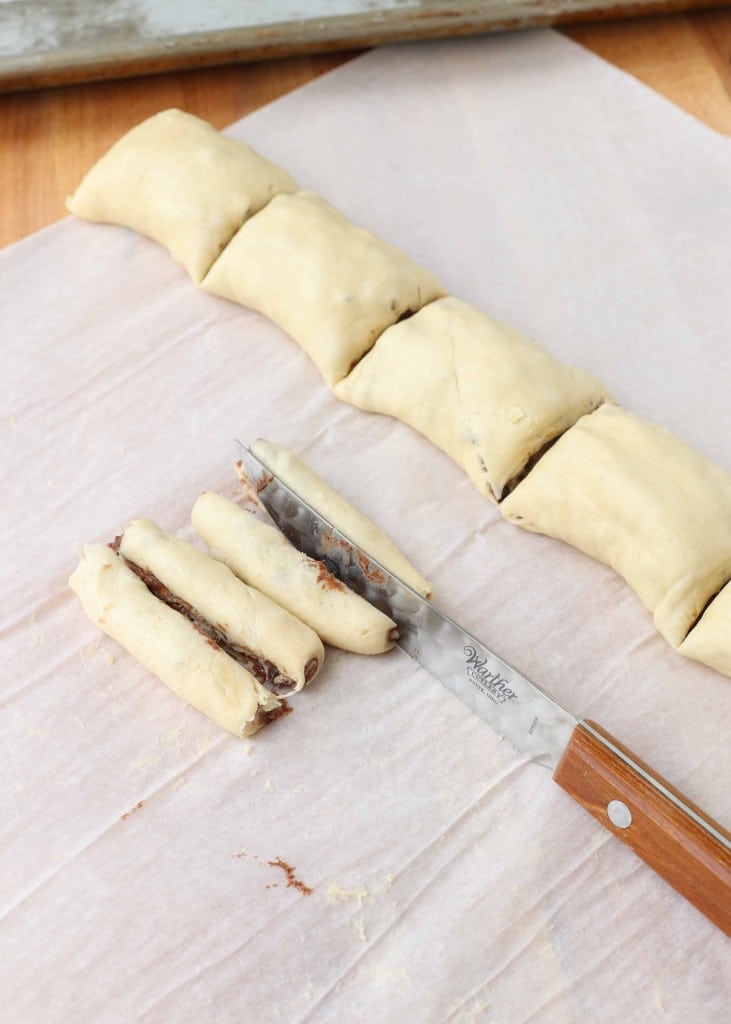 Overhead shot of wrapped puff pastry being cut with a thin knife