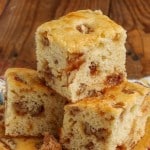 Horizontal close-up shot of sliced praline cake; in the background, a floral pattern hand towel