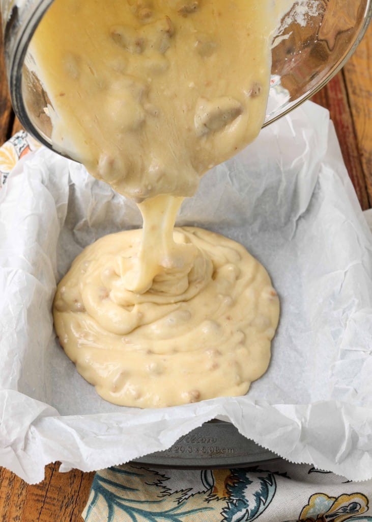 Vertical shot of cake batter mid-pour over a baking dish lined with parchment paper