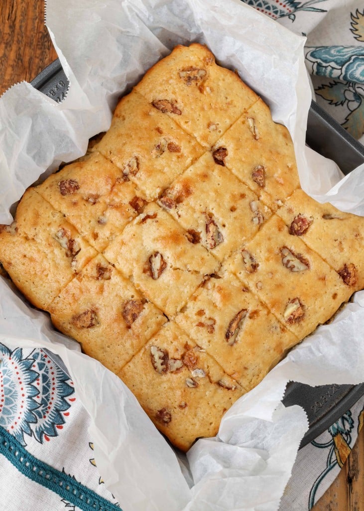 Overhead vertical shot of sliced praline cake in a baking dish lined with parchment paper